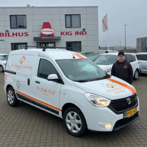 Hvid firmabil foran bilhus i Danmark