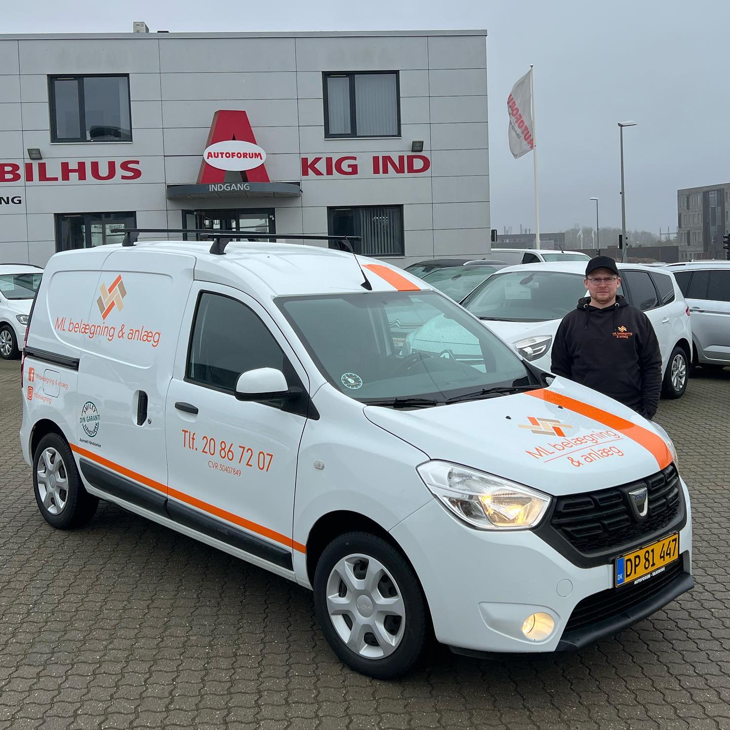 Hvid firmabil foran bilhus i Danmark