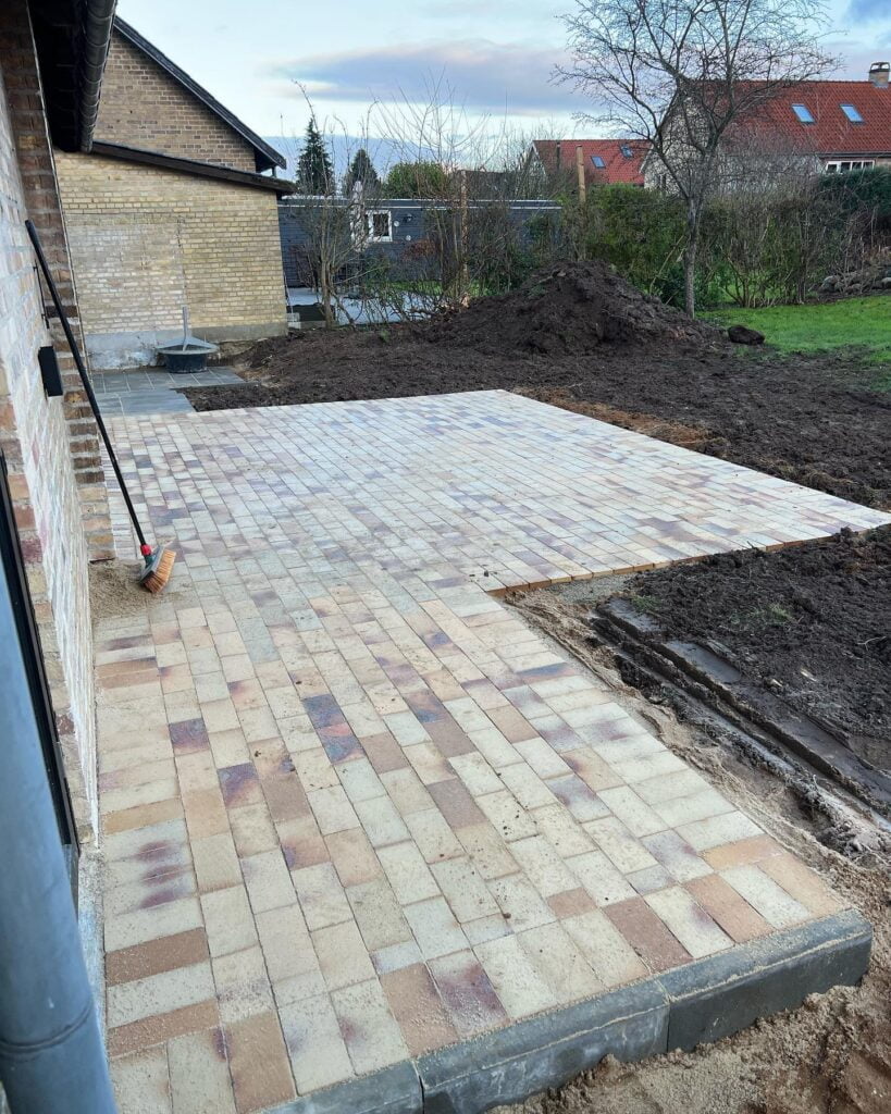 Ny belægning af terrasse i murstensfliser ved hus