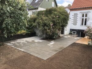 Ny flisebelagt terrasse ved hus og have