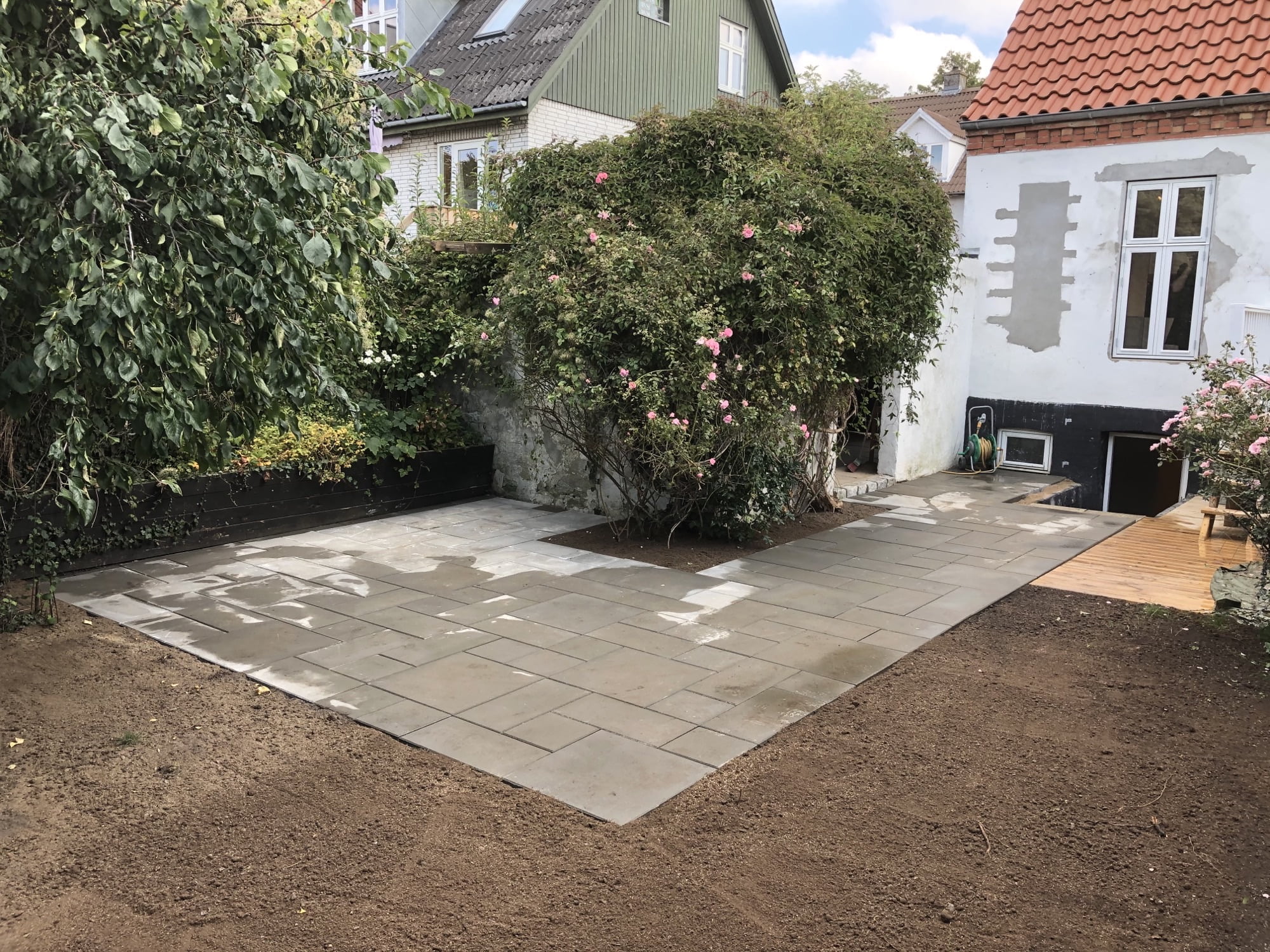 Ny flisebelagt terrasse ved hus og have