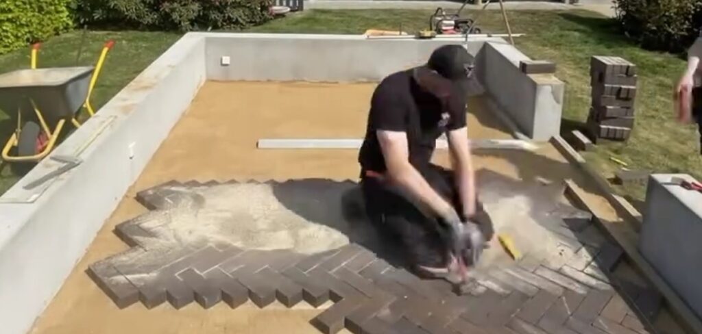 Person lægger mørke mursten på terrassebund